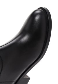 Black leather ankle boot with a rounded toe and low block heel, smooth finish, and visible stitching on the side.