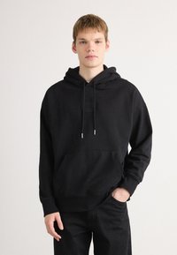 Zwarte hoodie van katoenmix, met een voorzak, trekkoorden met metalen uiteinden en een gestructureerde patch op de borst.
