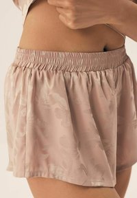 Pink floral shorts made from a soft, satin-like fabric with an elastic waistband and a relaxed fit, showcasing a subtle textured pattern.