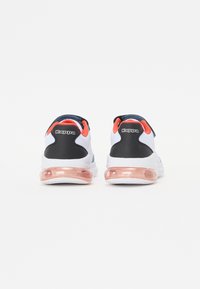 Chaussures de sport blanches avec un talon noir, des accents rouges et une semelle en gel transparente. Elles présentent un dessus en tissu texturé et un logo bien visible sur le talon.