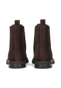 Bocanci de gleznă din suede maro cu părți elastice, accente negre, tălpi plate din cauciuc și o buclă la spate pentru a fi ușor de purtat.