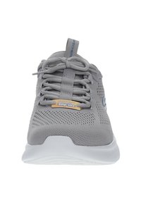 Scarpa sportiva grigia con tomaia in rete, logo e design con lacci. Presenta una suola imbottita e un'etichetta Slip-Ins ben visibile sul lato.