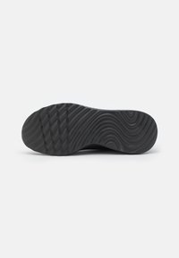 Black rubber shoe sole with a wavy texture and ridges for grip; features multiple horizontal grooves for traction.