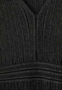 Zwarte geplooide jurkstof met een gestructureerde afwerking. V-hals ontwerp met glanzende draadjes, die een subtiele sprankeleffect creëren.