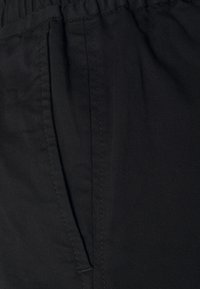 Pantaloni neri realizzati in un tessuto leggero e morbido, con una parte anteriore plissettata e una vita elastica per il massimo comfort.