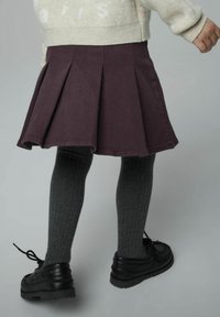 Gonna plissettata viola abbinata a calze a coste grigio scuro e scarpe nere, che mostrano una superficie di tessuto liscia e un design svasato.