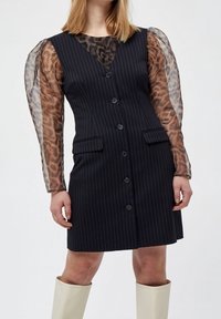 Schwarzes Nadelstreifen-Kleid mit tailliertem Schnitt, mit transparenten Ärmeln im Leopardenmuster, zwei vorderen Taschen und Knopfverschluss auf der Vorderseite.