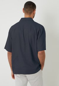 Kurzärmliges, dunkelblaues Hemd aus strukturiertem Stoff. Verfügt über einen klassischen Kragen und einen geraden Saum. Die Rückansicht zeigt keine sichtbaren Grafiken.