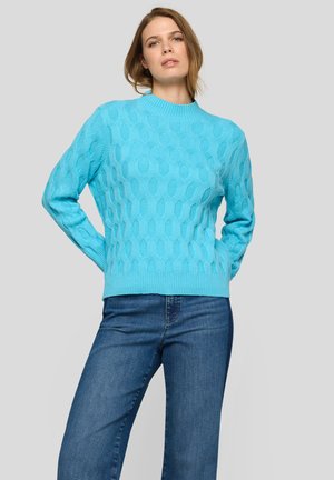 Türkisfarbener Strickpullover mit einem strukturierten Rautenmuster, Rundhalsausschnitt und geripptem Saum. Kombiniert mit blauen Jeans.