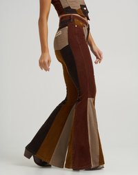 Corduroy flare broeken in bruin, beige en zwart met een patchwork ontwerp. Opvallende details zijn de contrasterende texturen en de strakke pasvorm rond de dij.