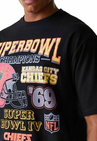 T-shirt en coton noir avec des textes et graphiques imprimés colorés, notamment "Champions du Super Bowl" et "Kansas City Chiefs '69."
