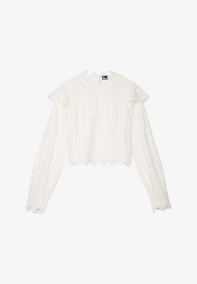 Witte lange mouw top met een getextureerd kantdesign, geschulpte randen en ruffles op de schouders. Verkorte lengte met een ronde halslijn.