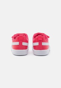 Zapatillas rosas con acentos blancos, tejido texturizado, forma redondeada y collar acolchado. Presenta un lazo para facilitar el uso y una suela blanca resistente.