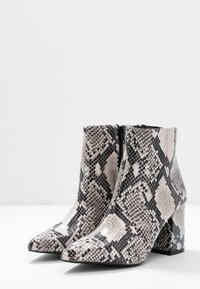 Snake-print ankle boots in gray and black, featuring a pointed toe and a block heel. Smooth texture with a zip closure at the back.