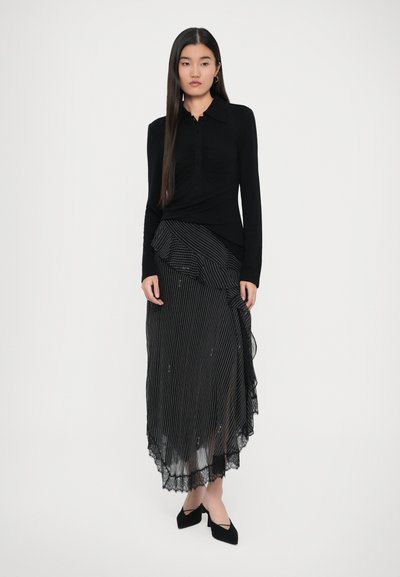 Top negro de manga larga con tapeta de botones, combinado con una falda de rayas negra y blanca en capas con un dobladillo con volantes y accents de encaje.
