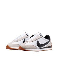 Scarpe atletiche bianche e grigie realizzate in suede e pelle, con uno swoosh nero, lacci bianchi e una suola in gomma marrone.