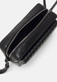 Borsa a tracolla in pelle nera con motivo trapuntato, chiusura a doppia zip e design elegante. L'interno include diversi scomparti.