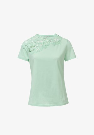 Camiseta verde menta clara hecha de una tela suave, con detalle de encaje floral en el hombro izquierdo y diseño clásico de cuello redondo.