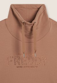 Haut de survêtement couleur rouille avec un col montant, doté de cordons de serrage avec embouts en métal et d'un texte embossé "FREDDY" orné de strass.