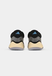 Scarpe da ginnastica nere con suola beige, caratterizzate da strisce grigie curve, un tallone testurizzato e accenti di branding blu.