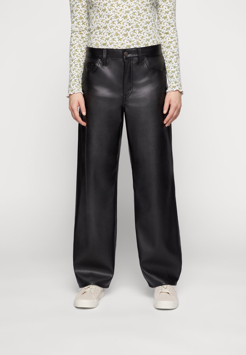 Zwarte neplederen wijde broek met een glanzende afwerking, voorzien van een knoop- en ritssluiting, voorzakken en een relaxed fit.