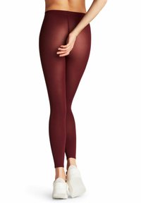 Leggings bordeaux realizzati in stoffa elasticizzata, con un alto punto vita e una superficie liscia. Indossati con scarpe con piattaforma bianche.