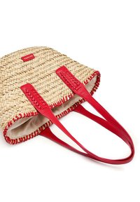 Sac fourré en paille tressée avec des sangles et des bordures en cuir rouge. Présente un design cousu et une étiquette logo rouge. L'intérieur est en tissu beige.