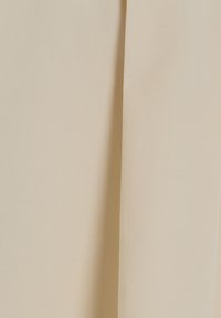 Beige stof met een gladde textuur, bestaande uit twee gevouwen secties. Het materiaal lijkt lichtgewicht en valt zacht.