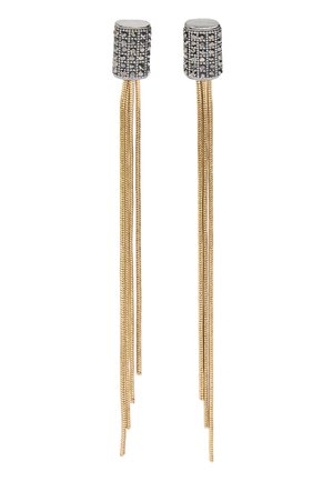 Srebrzyste cylindryczne kolczyki z czarnymi wzorami z ćwieków oraz długimi, cienkimi złotymi łańcuszkami zwisającymi jako kolczyki.