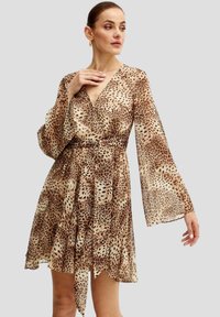 Abito con stampa leopardata, scollatura a V profonda, maniche lunghe svolazzanti e vita sfiancata. Realizzato in un tessuto leggero e testurizzato con gonna svasata.
