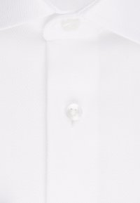 Camicia bianca con un tessuto testurizzato a righe diagonali, un colletto classico e un unico bottone bianco sul collo.