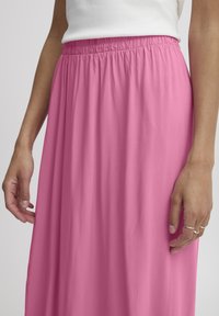 Falda maxi rosa, fluida, hecha de un tejido ligero con una cinturilla elástica; presenta una textura suave y un ajuste relajado.
