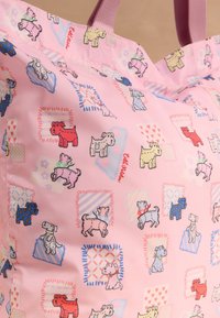 Rožinė audinio pirkinių krepšys su spalvingais animacinių šunų piešiniais, nešančiais šalikus ir antkaklius, supami raštuotų kvadratų ir širdelių.