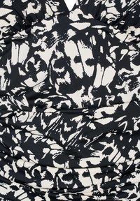 Tessuto elasticizzato a motivi in bianco e nero con design arricciato, caratterizzato da forme astratte e una consistenza morbida, adatto per capi di abbigliamento.