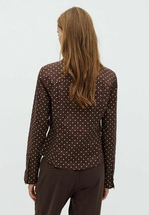 Pruunidega polka dot blouse, millel on vormiline disain, pikad varrukad ja nööpidega mansetid. Sile kangas kerge läikega, kergelt kohandatud taljeosa.