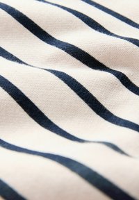 Könnyű anyag krémszínű fehér háttérrel és egyenletesen elhelyezkedő, vízszintes sötétkék csíkokkal, sima, enyhén gyűrött textúrával.