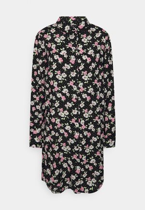 Chemise noire à manches longues et fermeture à boutons, comportant un motif floral en rose et blanc avec des accents verts. Tissu doux.