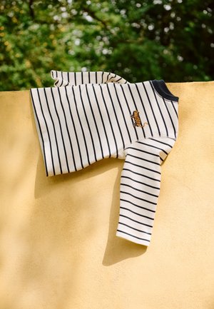 Ριγέ πουκάμισο μακρυμάνικο σε κρεμ και ναυτικό μπλε, με μικρή κέντημα τίγρης, κατασκευασμένο από απαλό ύφασμα με χαλαρή εφαρμογή και στρογγυλή λαιμόκοψη.