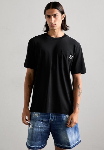 T-shirt in cotone nero con maniche corte, scollatura rotonda e taschino sul lato sinistro con dettaglio del logo bianco. Abbinato a pantaloni scuriti in denim.