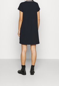 Námořnické šaty s krátkým rukávem z texturované tkaniny, s kulatým výstřihem a mírně áčkovým střihem, doplněné černými kotníkovými botami.
