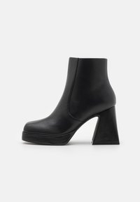 Botín negro hasta el tobillo hecho de cuero suave, con un tacón angular alto, suela con plataforma y diseño sin costuras con detalles de costura mínimos.