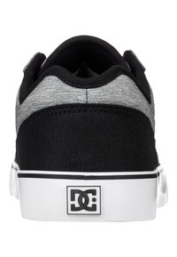 Black and gray canvas skate shoes with a white rubber sole and a branded heel logo. Features a textured upper and padded collar.