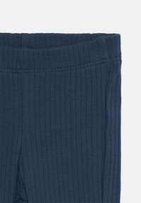 Leggings a coste navy con un elastico in vita, realizzati in un tessuto morbido ed elasticizzato. Texture liscia con righe verticali.