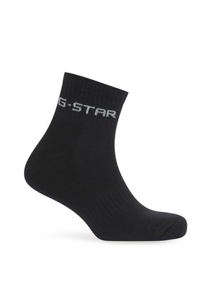 Chaussette cheville noire avec texture côtelée et texte blanc "G-STAR" près du bord supérieur, présenté sur fond blanc.