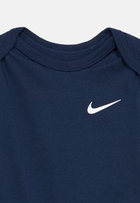 Tengerészkék pamut body kerek nyakkivágással; elöl apró fehér Nike logóval. Sima tapintású, rövid ujjú.