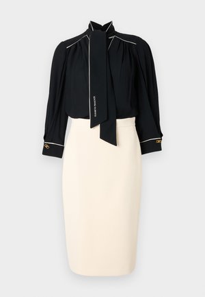 Blusa nera con collo alto e fiocco, caratterizzata da bordature bianche, maniche lunghe, e gonna a matita color crema con silhouette aderente e dettagli dorati.