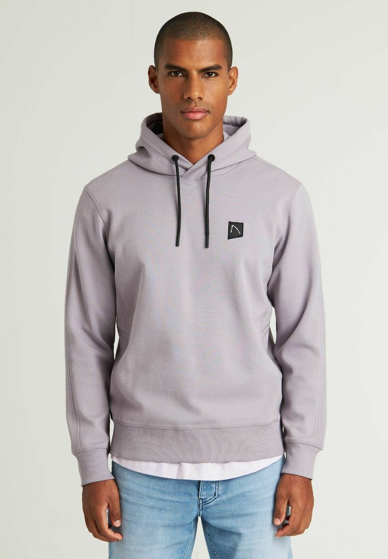 Sudadera de color púrpura claro con cordones, puños y dobladillo acanalados. Presenta un pequeño parche de logo negro en el pecho. Tejido texturizado.
