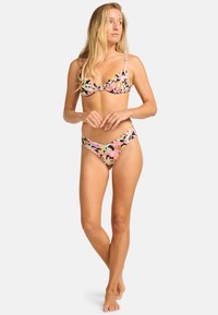 Conjunto de bikini floral con colores pasteles sobre un fondo oscuro. La parte superior tiene tirantes finos y un diseño de copa semi; la parte inferior es un brief de corte alto.