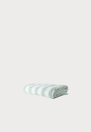 Folded towel with horizontal light gray and white stripes on a plain light background.
