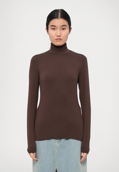 Pull à col roulé marron en tissu doux, avec des manches longues et une silhouette ajustée, associé à une jupe en denim clair.
